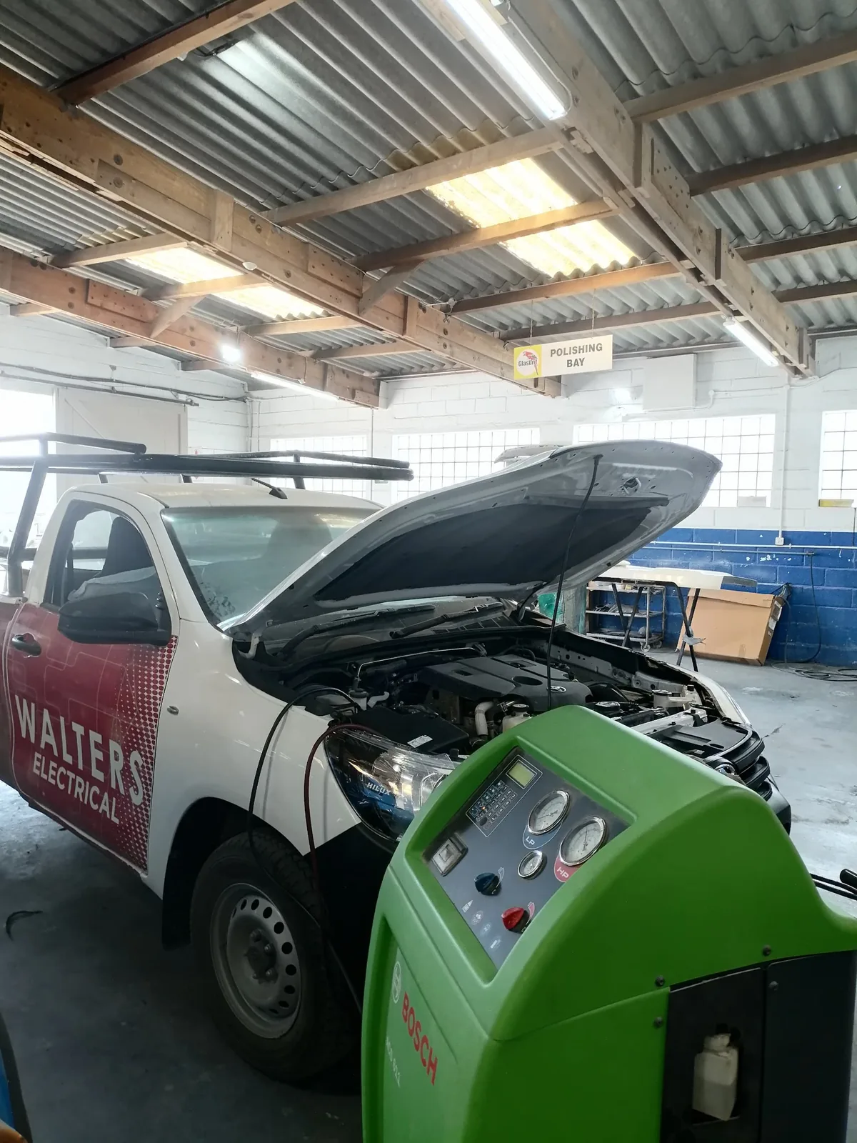 White bakkie with its bonnet open inside the workshop