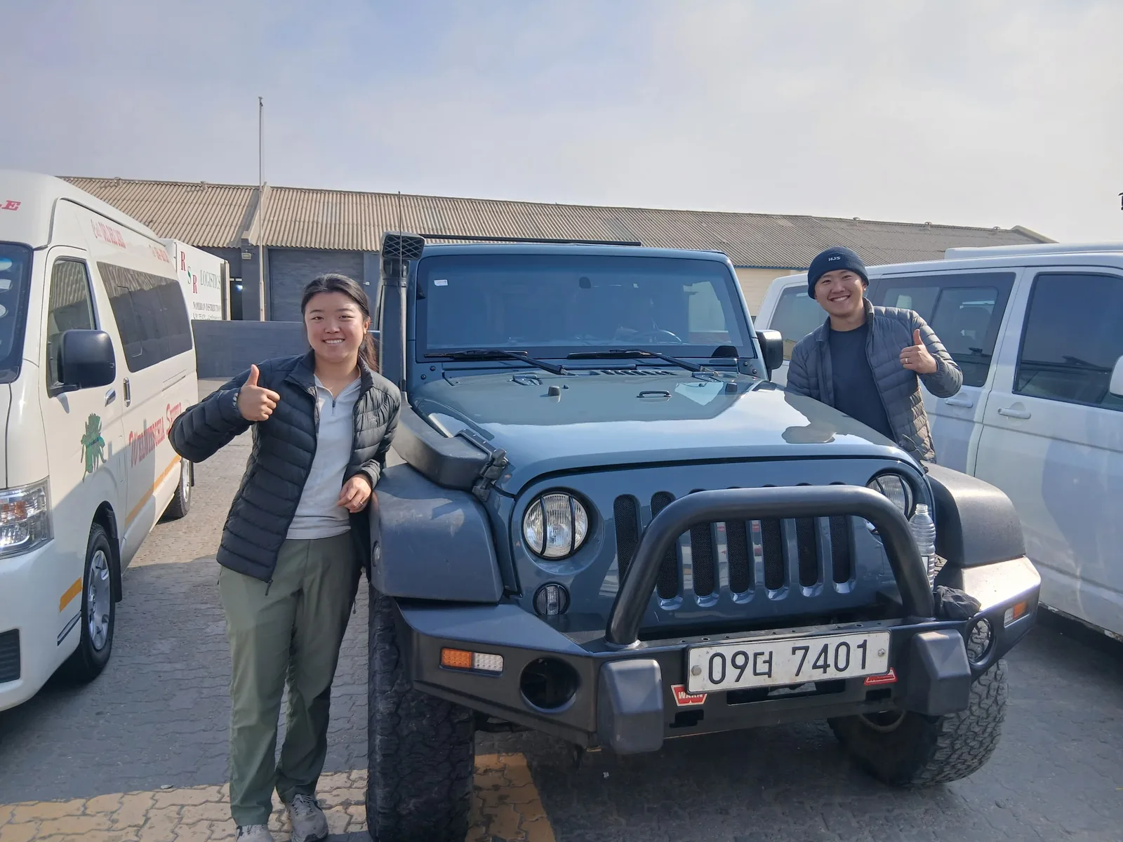 Two customers giving a thumbs up beside their Jeep Wrangler in the Mototec yard