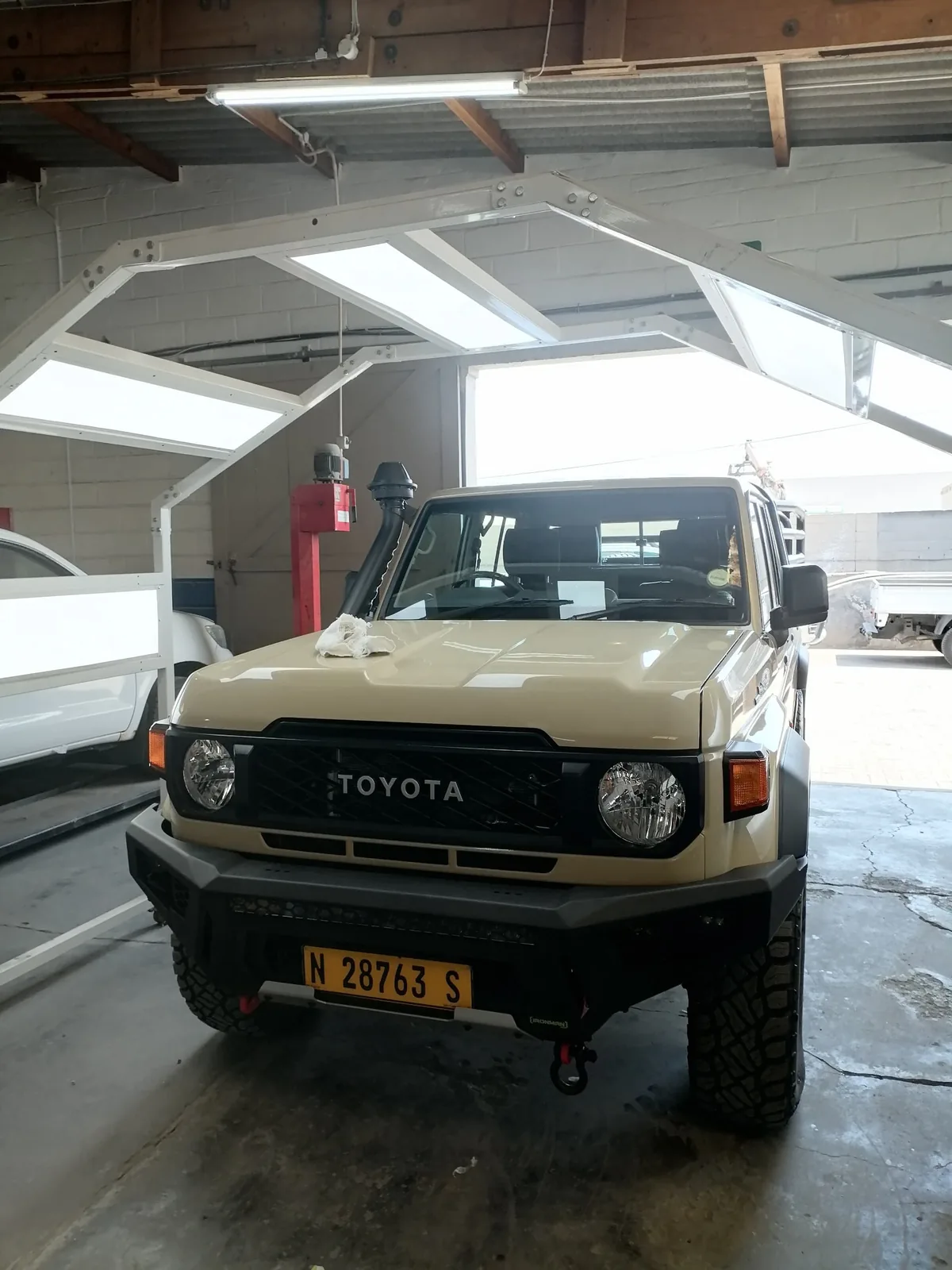 Beige 4x4 under the lights inside the workshop